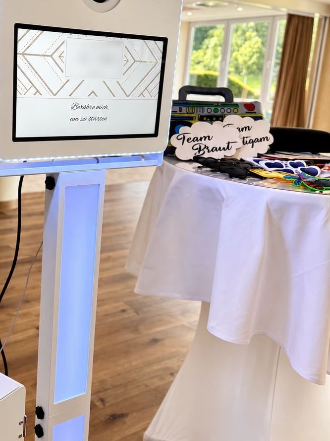 Fotobox-Touchscreen mit persönlichem Startbildschirm und Requisitentisch mit Team-Braut-Schildern auf einer Hochzeit im l’Arrivée Hotel und Spa in Dortmund